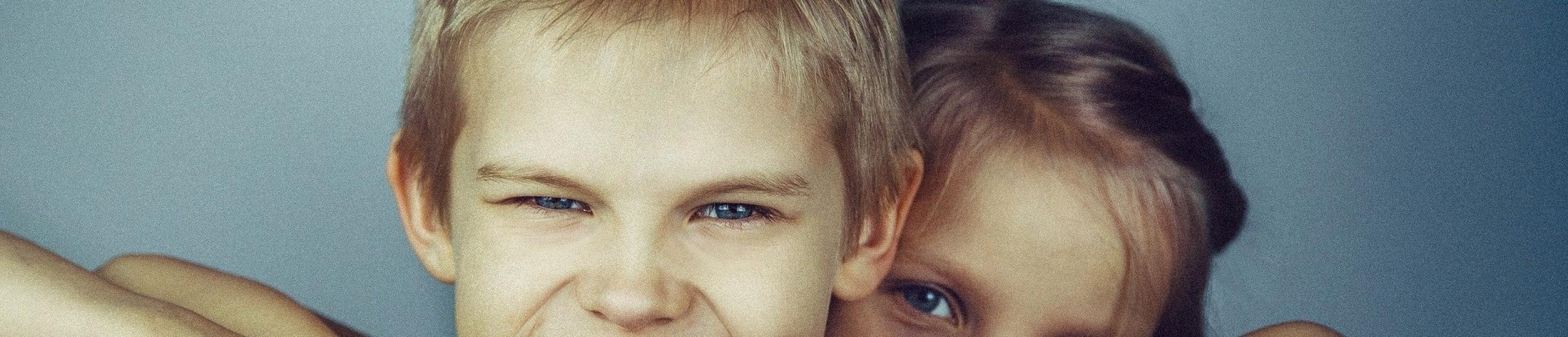 Foto di una ragazzino con dietro una ragazzina che si affaccia sopra la sua spalla