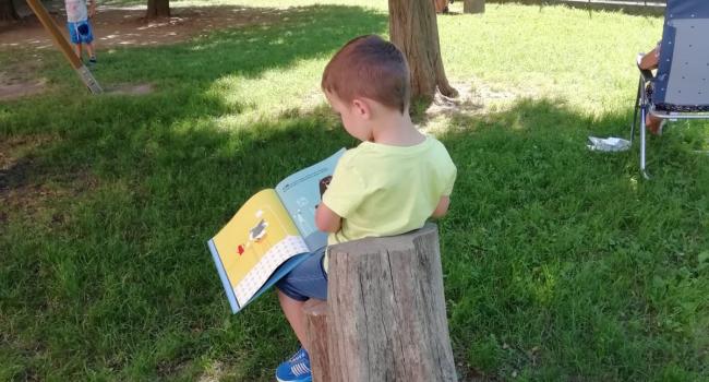 Foto di bimbo che legge ai Giardini "Mainetto"
