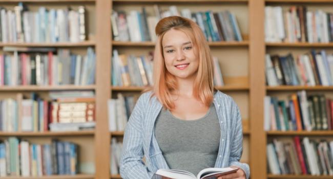 Immagine di ragazza in biblioteca, scaffali con i libri sfocati